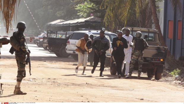 Des personnes s'éloignent en courant de l'hôtel Radisson, à Bamako, où se déroule une prise d'otages, le 20 novembre 2015.