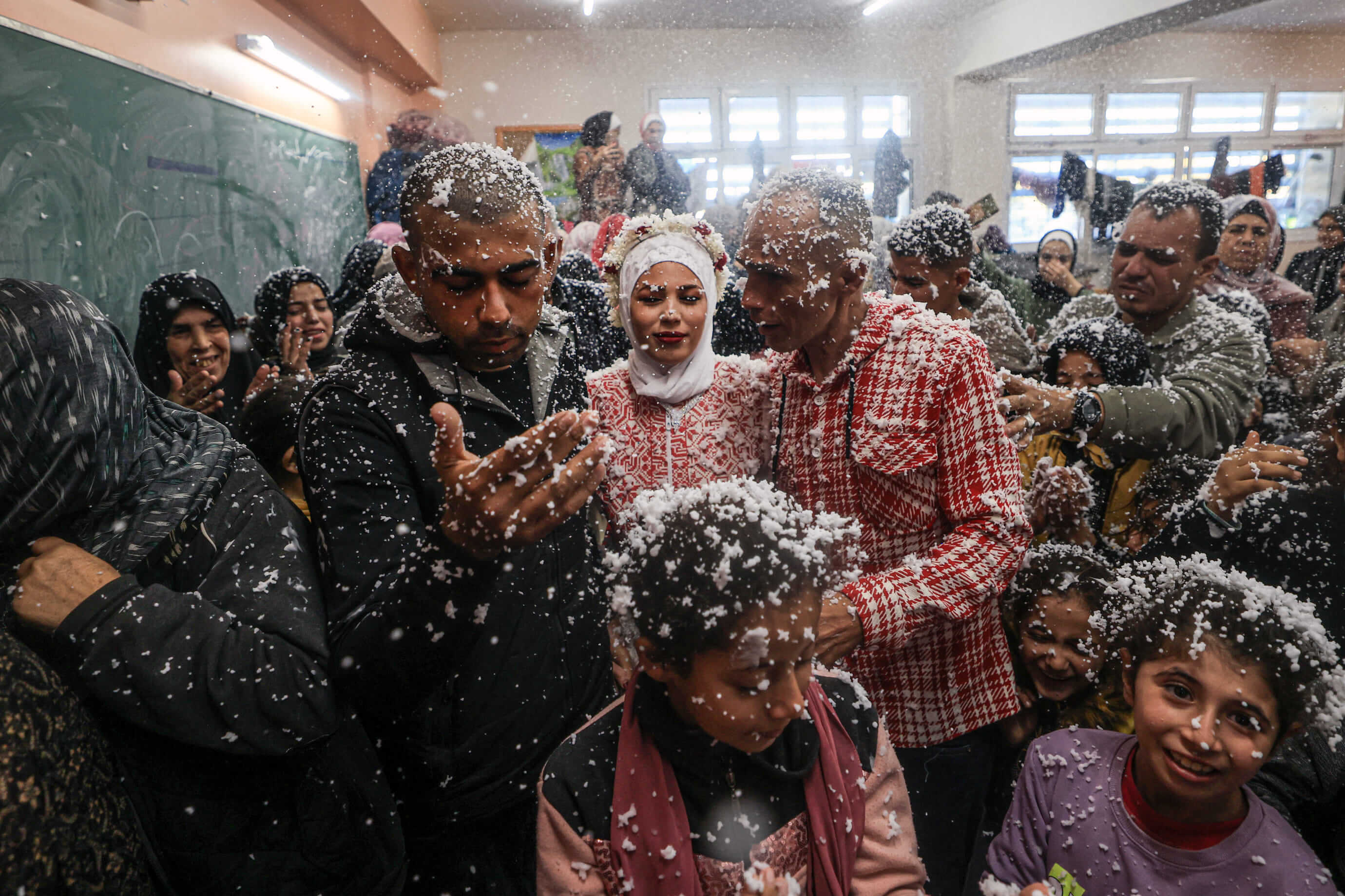 Afnan Jibril (au centre) et Mustafa Shamlakh (à gauche) fêtent leur mariage entourés d'invités dans une école de l'UNRWA à Rafah, le 12 janvier 2024. (MAHMUD HAMS / AFP)