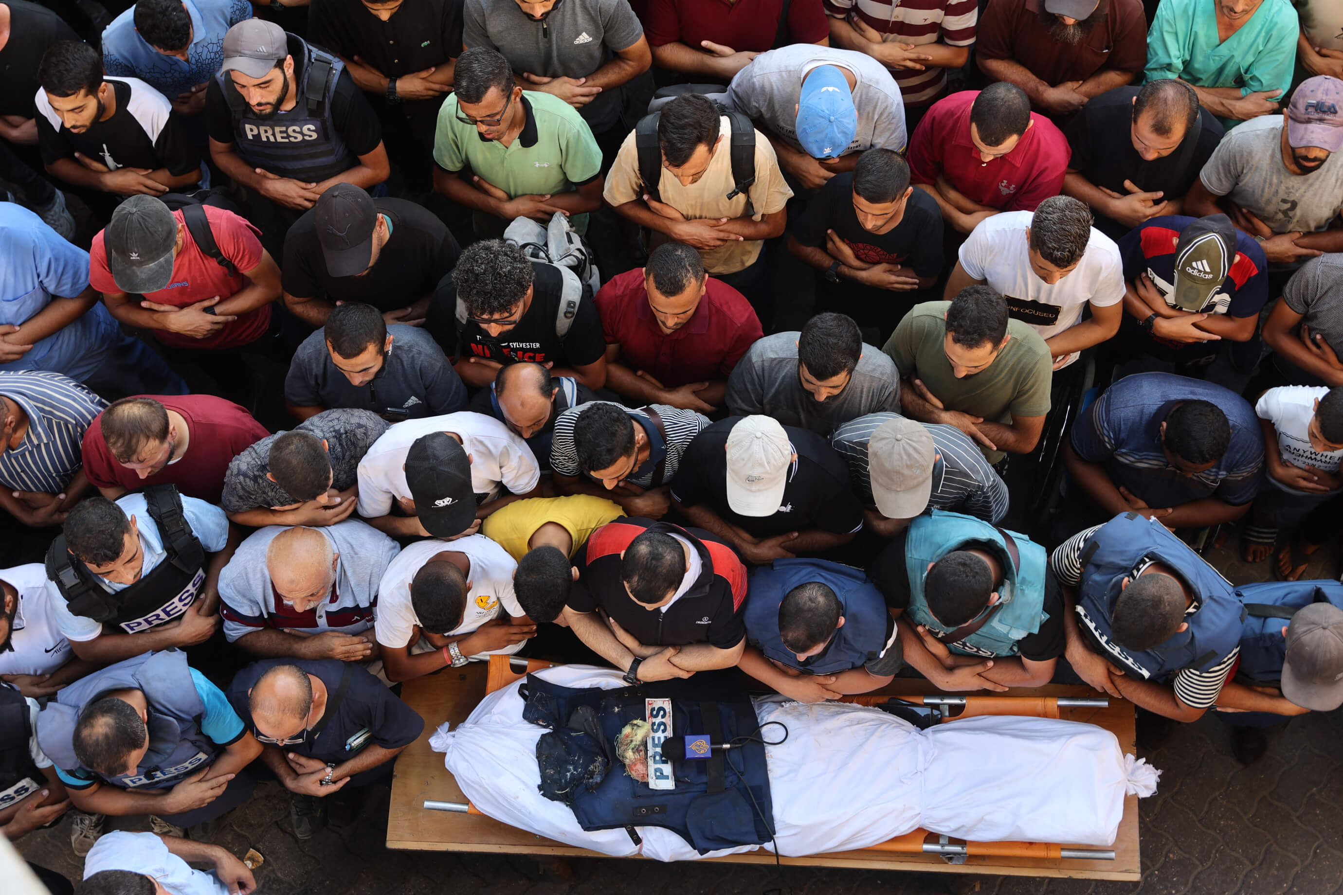 Des hommes se recueillent devant la dépouille du reporter d'Al-Jazeera Ismail al-Ghoul, tué avec son cameraman Rami al-Refee lors d'un bombardement israélien dans le camp de réfugiés d'al-Shati, le 31 juillet 2024. (OMAR AL-QATTAA / AFP)