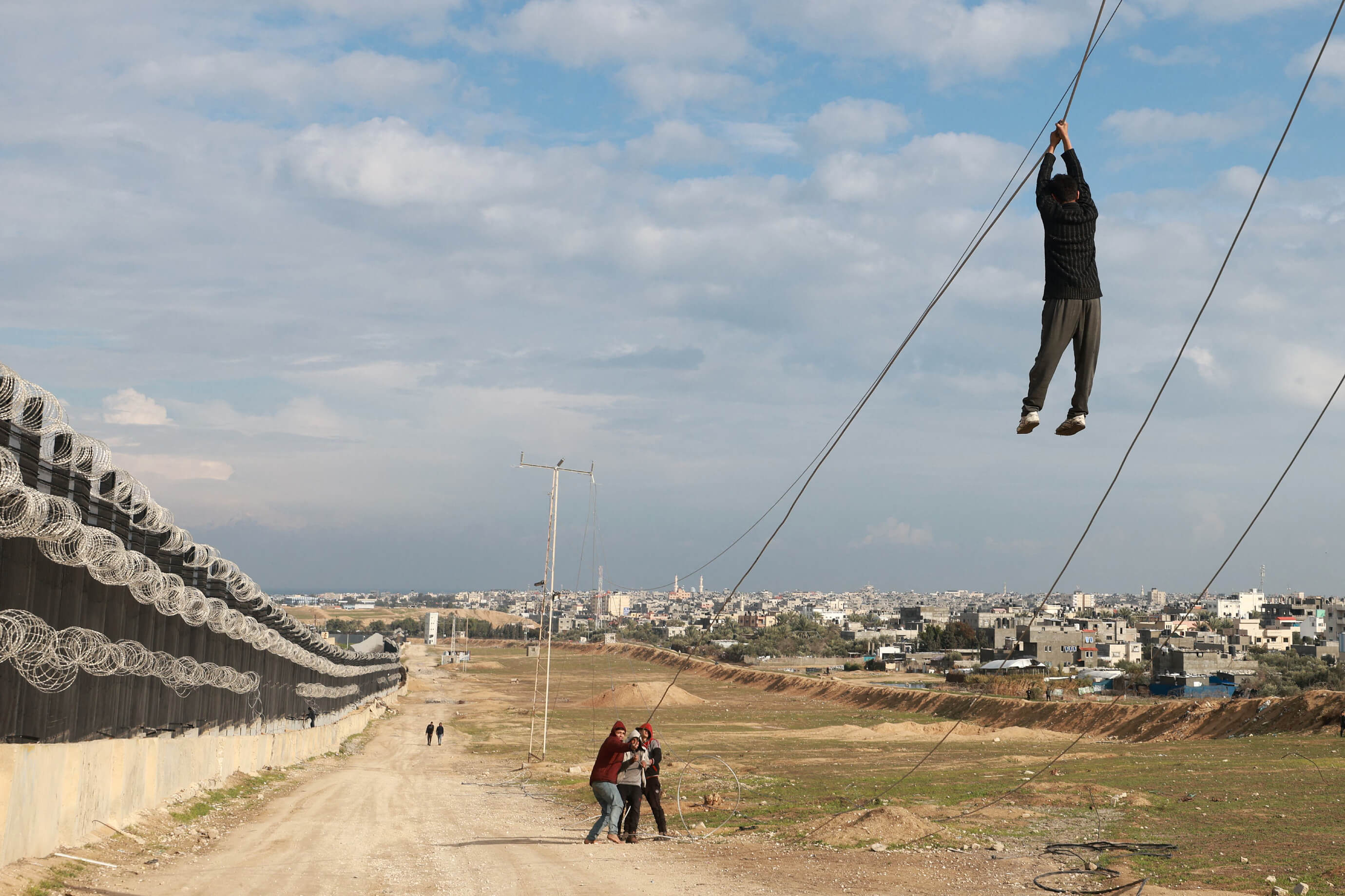 Des enfants palestiniens déplacés jouent avec un câble électrique hors de fonctionnement entre la frontière entre la bande de Gaza et l'Egypte, à Rafah, le 16 février 2024. (MOHAMMED ABED / AFP)