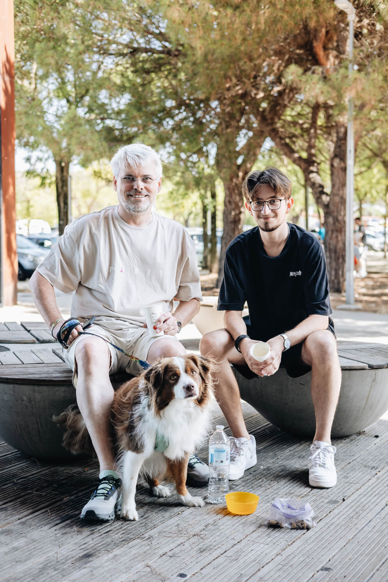 un père, son fils et leur chien assis dans un parc