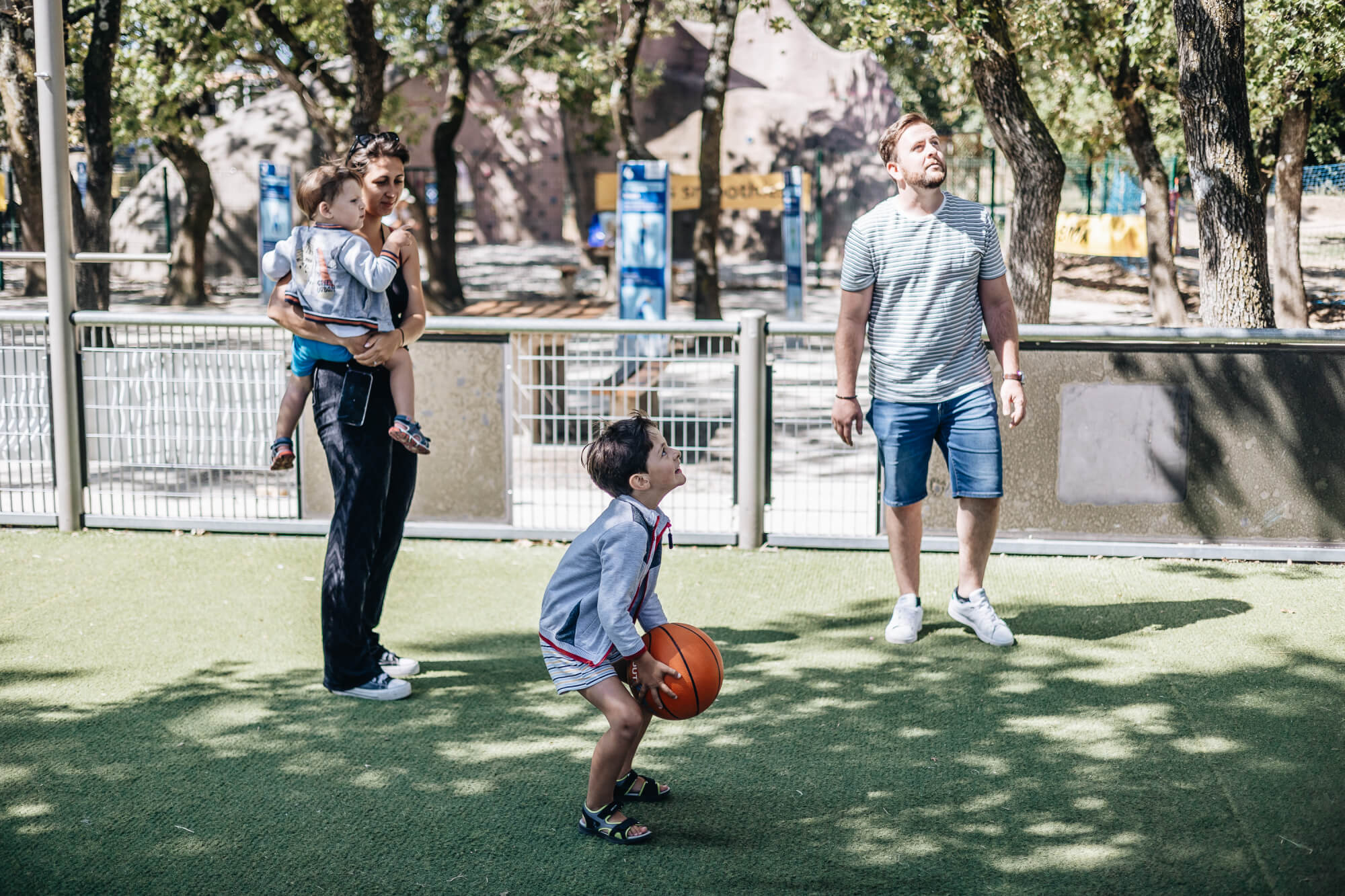 enfant jouant sur un city stade avec sa famille