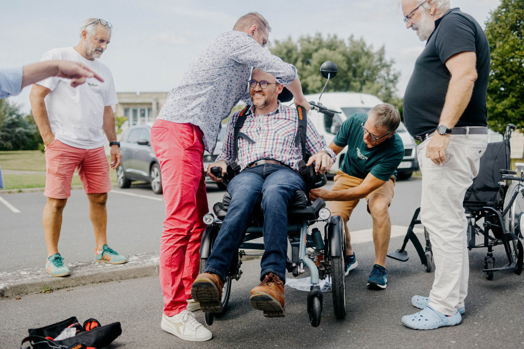 Des membres du Normandy installent Yoann sur le siège avant de son vélo pousseur. Pour cet employé du diocèse de Coutances qui ne peut pas marcher, ″rouler, c'est synonyme de liberté″. (PIERRE MOREL / FRANCEINFO)