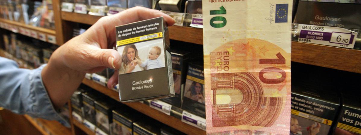 Achat d\'un paquet de cigarettes dans un bureau de tabac avec un billet de dix euros.