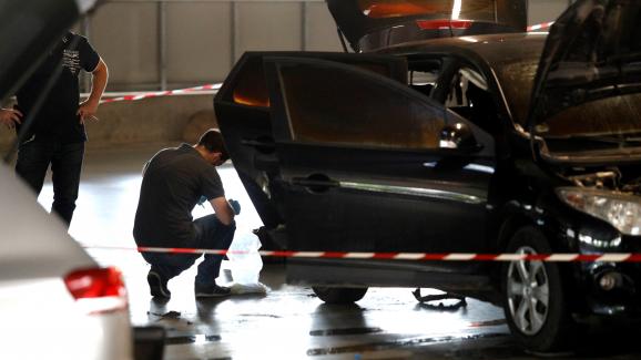 Un officier de police se tient à côté du véhicule utilisé pour l\'évasion de Redoine Faïd et abandonné dans le parking du centre commercial O\'Parinor, à Aulnay-Sous-Bois, au nord de Paris, le 1er juillet 2018.