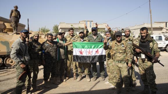 Des membres de l\'Armée nationale syrienne posent avec un drapeau syrien en arrivant à Tell Abyad, en Syrie, dans le cadre de l\'offensive menée par la Turquie, le 10 octobre 2019.&nbsp;