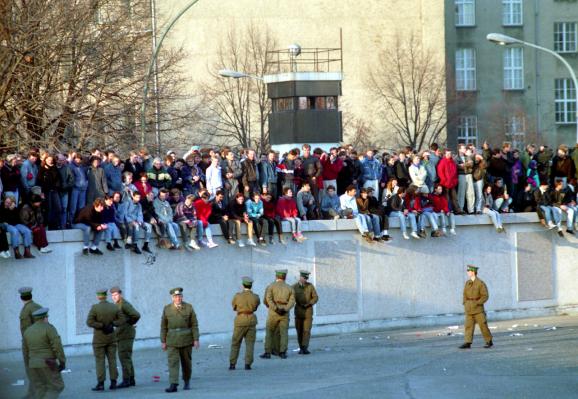 Une foule se dresse sur le mur de Berlin tandis que des soldats les surveillent d\'en bas, le 10 novembre 1989.