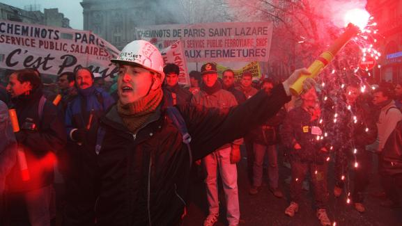 Un cheminot brandit un fumigène, lors d\'une manifestation contre le plan Juppé, le 5 décembre 1995, à Paris.