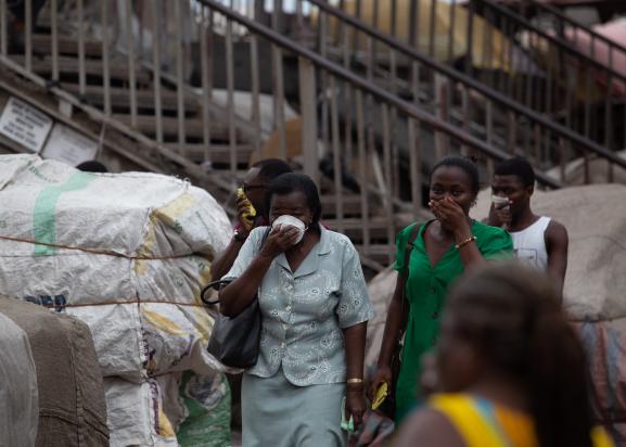 Des passants se protègent pendant une opération de désinfection contre le coronavirus sur un marché d\'Accra (Ghana) le 23 mars 2020.&nbsp;