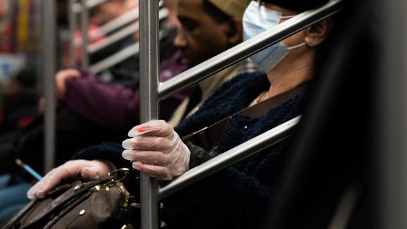 Une femme porte des gants et un masque pour se protéger des germes dans le métro de New York (Etats-Unis), le 9 mars 2020.