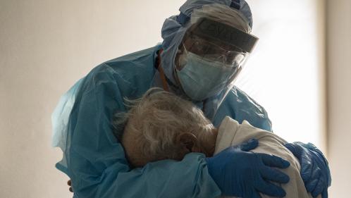 Symbole de l'épidémie de Covid-19, cette photo d'un médecin masqué de la tête aux pieds qui réconforte un malade âgé devient virale