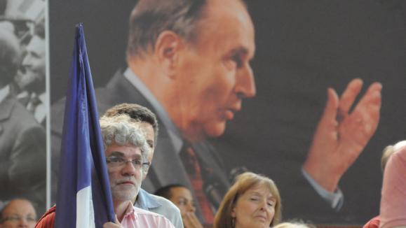 Portrait de François Mitterrand affiché derrière des militants socialistes, à Paris (France) le 8 mai 2011