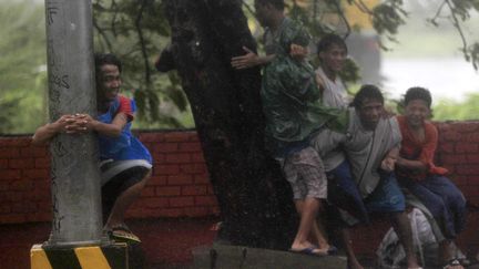 Des jeunes gens se mettent &agrave; l'abri pendant &nbsp;le passage du typhon Rammasun &agrave; Manille (Philippines), le 16 juillet 2014. (ROMEO RANOCO / REUTERS)