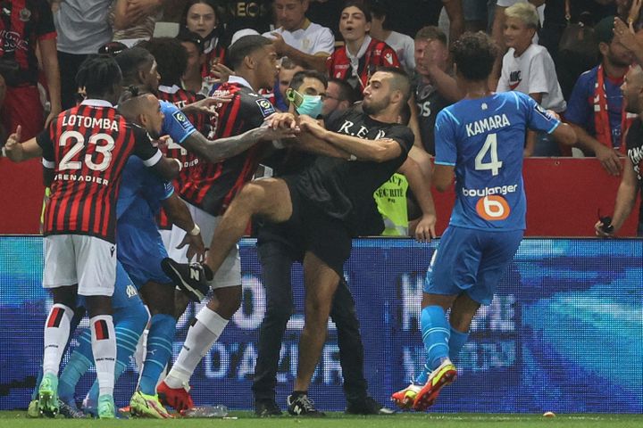 Un supporter tente de s'en prendre à Dimitri Payet lors de l'envahissement du terrain de l'Allianz Riviera en marge de Nice-Marseille, le 22 août 2021. (VALERY HACHE / AFP)