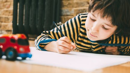 Image d'illustration montrant un enfant en train d'écrire sur une feuille de papier. (BONFANTI DIEGO / CULTURA CREATIVE / AFP)