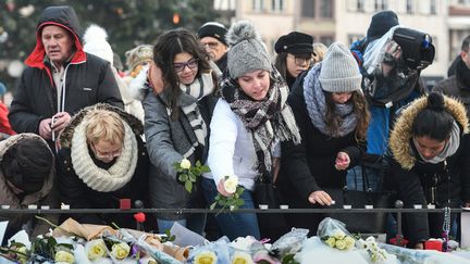 Des passants déposent des fleurs place Kléber à Strasbourg le 16 décembre 2018,&nbsp;cinq jours après l'attentat du marché de Noël. (SEBASTIEN BOZON / AFP)