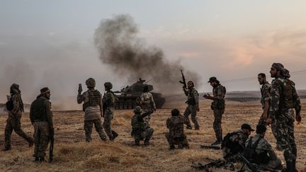 Des soldats turcs et des combattants syriens soutenus par la Turquie rassemblés dans la banlieue nord de la ville syrienne de Manbij, près de la frontière turque, le 14 octobre 2019. (ZEIN AL RIFAI / AFP)