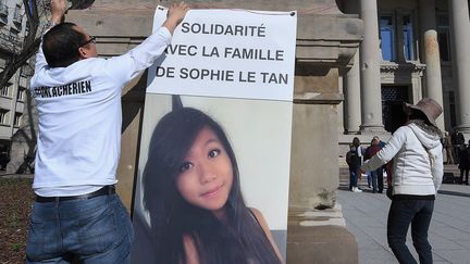 Le père de Sophie Le Tan accroche un portrait de sa fille, le 28 mars 2019, devant le tribunal de Strasbourg (Bas-Rhin). (PATRICK HERTZOG / AFP)