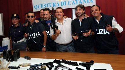 En 2010, des policiers italiens posent devant leur butin, un arsenal récupéré à Cosa Nostra. (MARCELLO PATERNOSTRO / AFP)