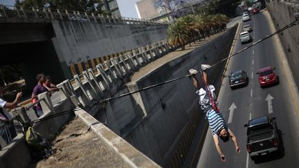 Un jeune gar&ccedil;on joue au funambule au-dessus d'une route de&nbsp;Guatemala City (Guatemala), le 24 f&eacute;vrier 2013 (JORGE LOPEZ / REUTERS)