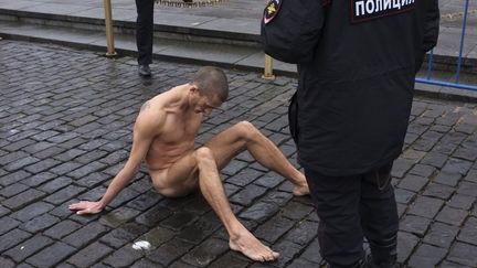 Des policiers russes encerclent l'artiste&nbsp;Piotr Pavlenski, qui a clou&eacute; la peau de ses testicules entre des pav&eacute;s de la place Rouge, &agrave; Moscou&nbsp;(Russie),&nbsp;le 10 novembre 2013.&nbsp; (MAXIM ZMEYEV / REUTERS)