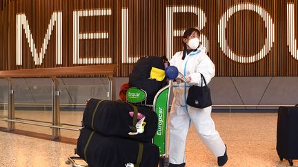 Une&nbsp;voyageuse&nbsp;porte une combinaison personnelle de protection contre le Covid-19,&nbsp;le 29 novembre 2021, à l'aéroport de Melbourne en Australie,&nbsp;alors que les&nbsp;premiers cas de contamination au variant Omicron du virus ont été enregistrés dans le pays. (WILLIAM WEST / AFP)