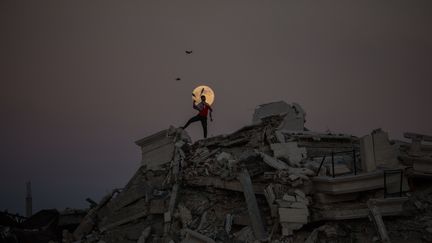 Un jeune Palestinien jongle, perché sur les ruines d'un bâtiment détruit par les bombardements de l'armée israélienne, tandis que la "super Lune" éclaire le camp de réfugiés d'Al-Bureij, le 15 novembre 2024, dans la bande de Gaza. (MAJDI FATHI / NURPHOTO / AFP)