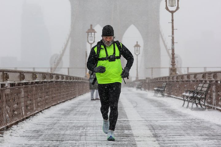 A man jogs across the Brooklyn Bridge in New York on Jan. 29, 2022.   (TAYFUN COSKUN / ANADOLU AGENCY / AFP)