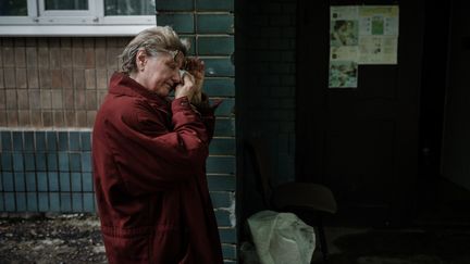 Une femme essuie ses larmes à l'entrée d'un abri à Lyssytchansk, dans l'Est de l'Ukraine, le 14 mai 2022. (YASUYOSHI CHIBA / AFP)