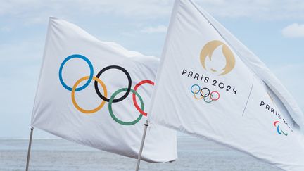 Le drapeau olympique et de Paris 2024 sur la plage de Teahupo'o, en Polynésie française, le 11 novembre 2021. (VAIKEHU SHAN / HANS LUCAS / AFP)