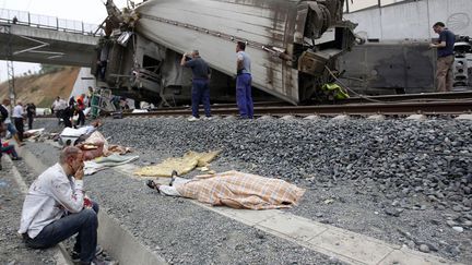 Un passager bless&eacute; est assis pr&egrave;s du corps d'une des victimes du train qui a d&eacute;raill&eacute; pr&egrave;s de Saint-Jacques-de-Compostelle (Espagne), le 24 juillet 2013. (REUTERS)