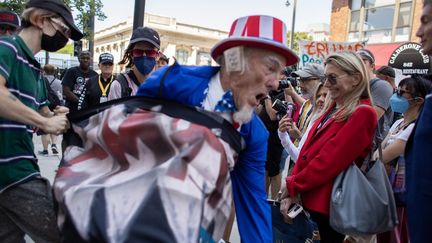 Pansement sur l'oreille, un supporter de Donald Trump costumé tente d'arracher une bannière devant le centre où se tient la convention républicaine, le 18 juillet 2024. (JIM VONDRUSKA / GETTY IMAGES NORTH AMERICA / AFP)