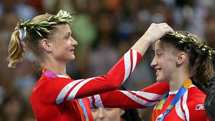 Les gymnastes russes Svetlana Khorkina et Natalia Ziganchina, couronnées d''olivier et portant leurs médailles de bronze, après leur victoire en équipe lors des Jeux d'Athènes en 2004. (LOUISA GOULIAMAKI / EPA / MAXPPP)