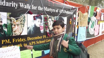 Un &eacute;tudiant devant le mur en hommage aux victimes de l'attaque de l'&eacute;cole de Peshawar, au Pakistan, le 22 d&eacute;cembre 2014. (MUSARRAT ULLAH / CITIZENSIDE.COM / AFP)