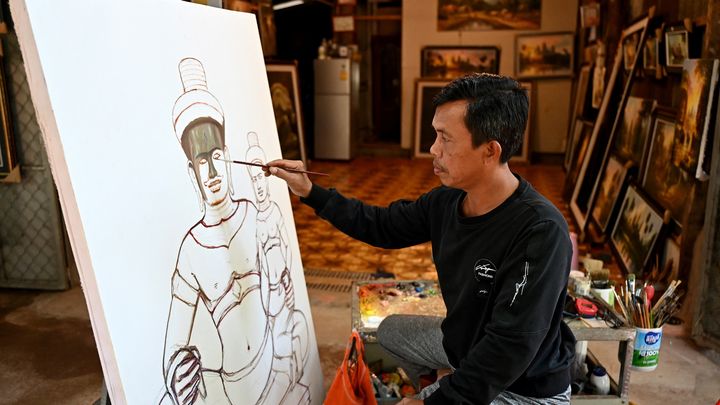 Le peintre Chan Vichet peignant les temps d'Angkor au Cambodge, en 2023 (TANG CHHIN SOTHY / AFP)