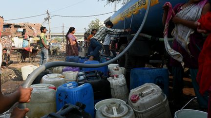 Des habitants font le plein d'eau dans un bidonville de New Delhi (Inde), le 18 mars 2015. (MONEY SHARMA / AFP)