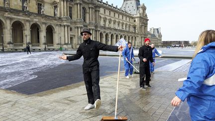 L'artiste JR avec des bénévoles, le 28 mars 2019, pour la réalisation de son œuvre qui célèbre les 30 ans de la pyramide du Louvre. (ANNE CHÉPEAU / FRANCE-INFO)