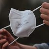 Une femme s'apprête à enfiler un masque FFP2 à L'Aquila (Italie), le 28 décembre 2021. (LORENZO DI COLA / NURPHOTO / AFP)