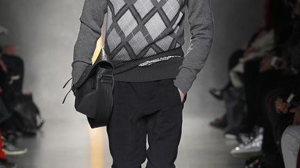 Bottega Veneta : relax et informelle, la collection dessinée par Tomas Maier pour qui le vêtement se doit d'être une sorte d'uniforme qui allierait la "désinvolture du sportswear à la sophistication", est d'un classicisme intemporel. "La collection explore la versatilité d'un look qui peut être parfait pour chaque situation", explique le styliste. Les pantalons, en laine d'agneau douce et confortable, sont serrés aux chevilles. Le bonnet se pose sur les oreilles, vers l'avant et les sacs au motif "intrecciato" (entrelacé) caractéristique sont immenses, pliés en deux. Les costumes Prince de Galles sont modernisés par une touche tye-and-dye vert olive ou bleu au bas des vestes et les Loden prennent un coup de jeune.
 (Bottega Veneta)