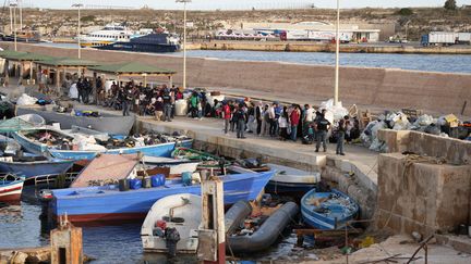 Des migrants attendant au port de Lampedusa à leur arrivée, le 18 septembre 2023 (ZAKARIA ABDELKAFI / AFP)