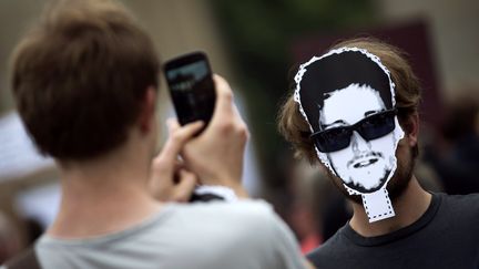 Un manifestant prend une photo d'un homme portant un masque d'Edward Snowden, pendant une manifestation &agrave; Berlin (Allemagne), le 4 juillet 2013.&nbsp; (THOMAS PETER / REUTERS )