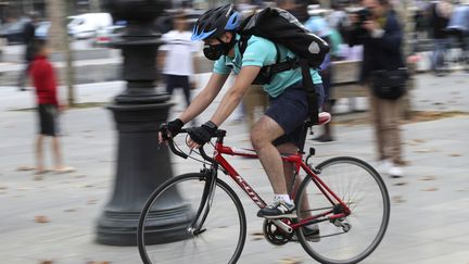 Un livreur à vélo dans une rue de Paris. (JACQUES DEMARTHON / AFP)