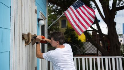 Un homme protège&nbsp;un magasin à&nbsp;Wrightsville (Caroline du Nord, Etats-Unis), à l'approche de l'ouragan Florence, le 11 septembre 2018.&nbsp; (LOGAN CYRUS / AFP)