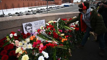 Une femme dépose des fleurs sur le pont où a été assassiné Boris Netmsov en 2015. (EVGENY ODINOKOV / SPUTNIK / AFP)