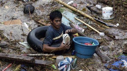 Un Philippin avance dans une mare de d&eacute;bris, apr&egrave;s le passage meurtrier de la temp&ecirc;te tropicale Washi, le 17 d&eacute;cembre 2011.