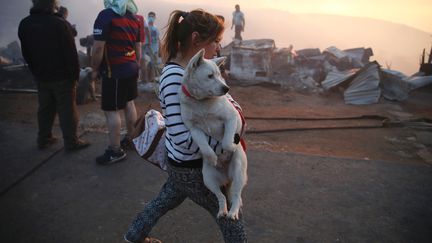 Une femme tient son chien dans les bras pour le sauver des flammes. (RODRIGO GARRIDO / REUTERS)