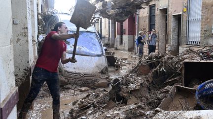 Pelle à la main, un homme nettoie une rue de Paiporta. (JOSE JORDAN / AFP)