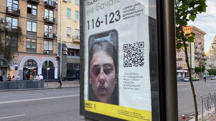 Une affiche de l'ONG Amnesty International indiquant le numéro de téléphone d'urgence pour les femmes victimes de violences, à Kiev (Ukraine), en juin 2022. (BORIS LOUMAGNE / RADIOFRANCE)