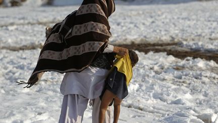 Un Afghan porte son fils pour traverser une rue enneig&eacute;e &agrave; Kaboul (Afghanistan), le 10 janvier 2013. (OMAR SOBHANI / REUTERS)