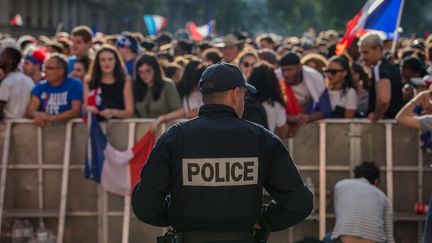 Un policier&nbsp;en faction à proximité de supporters français, à l'Hôtel de Ville à Paris, le 10 juillet 2018. (AURELIEN MORISSARD / MAXPPP)